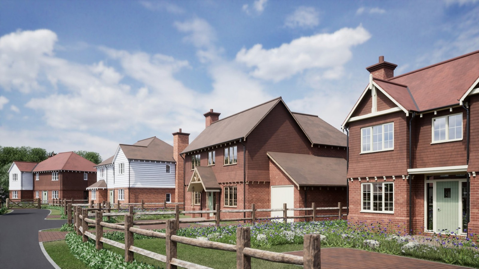 A row of newly built red brick houses on a UK housing development, with a post and rail fence along the road
